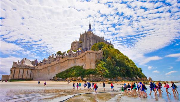 Groupe de touristes traversant les sables vers le Mont-Saint-Michel